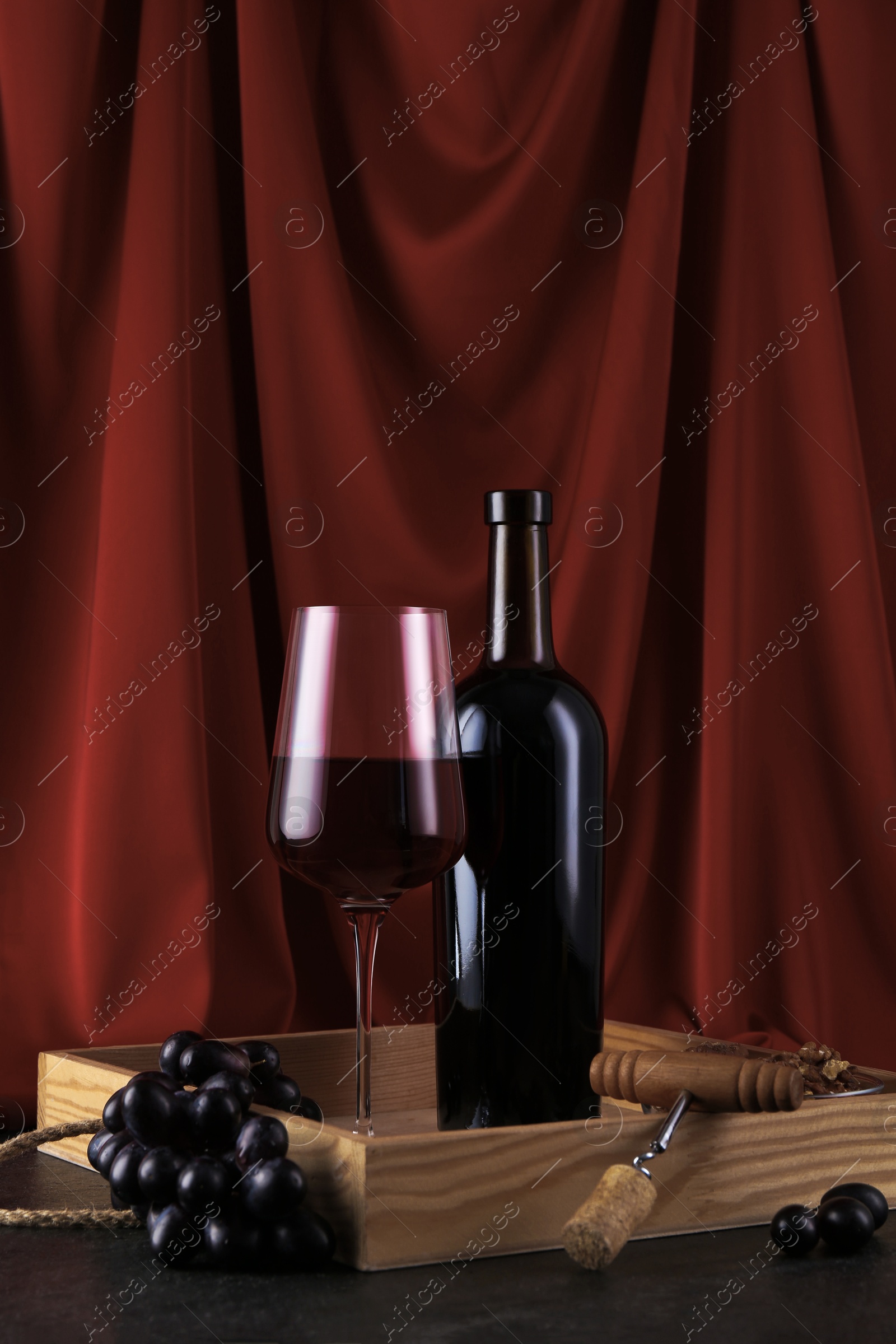 Photo of Corkscrew, glass of wine, bottle and grapes on table