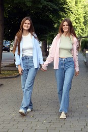 Photo of Twin sisters holding hands while walking outdoors