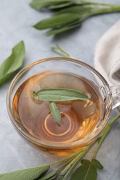 Photo of Aromatic herbal tea with sage on grey table, closeup