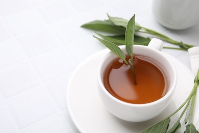 Photo of Aromatic herbal tea in cup with sage on white table, space for text