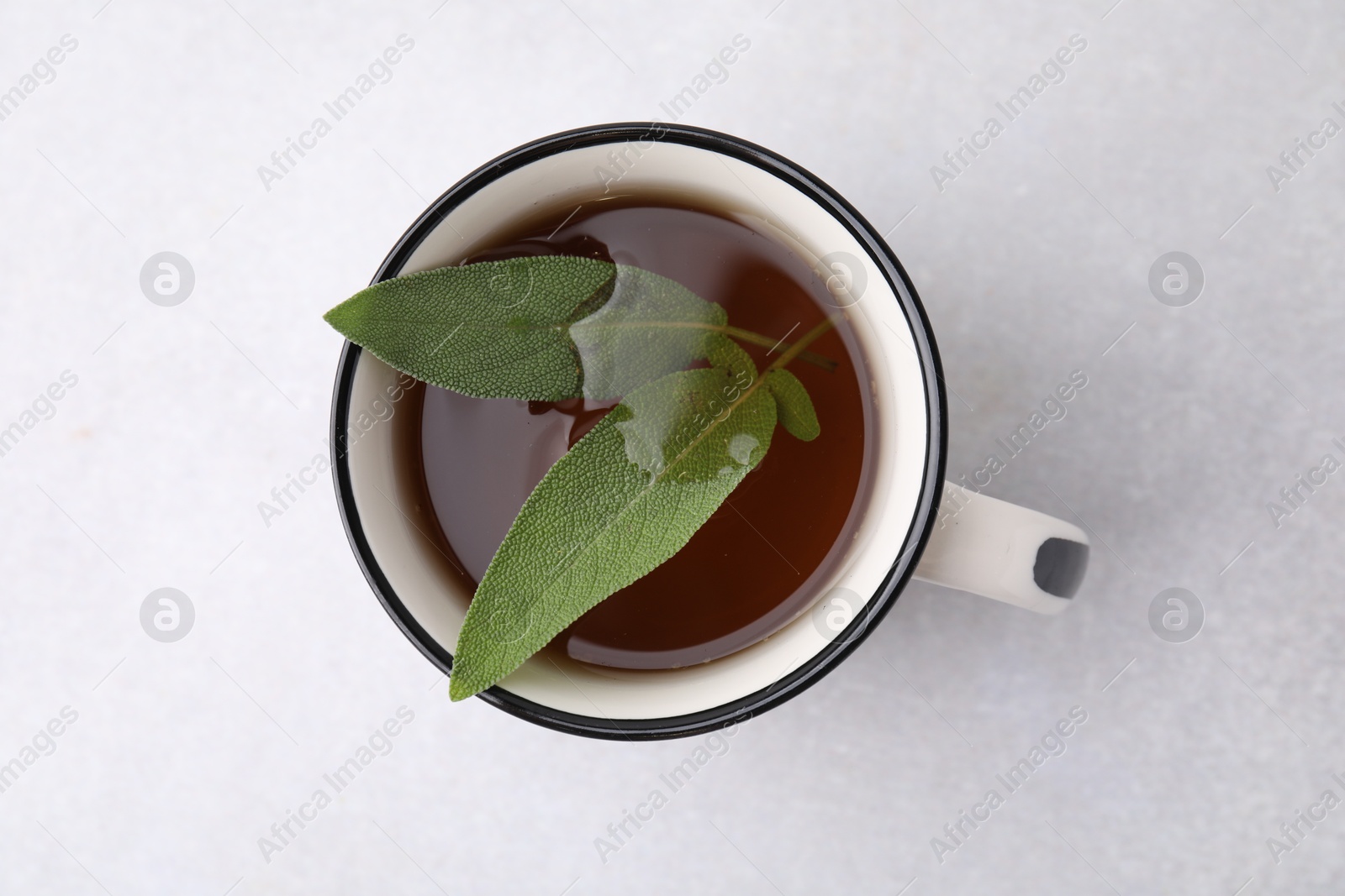 Photo of Aromatic herbal tea with sage in mug on light table, top view