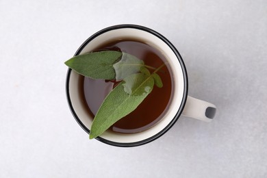 Photo of Aromatic herbal tea with sage in mug on light table, top view