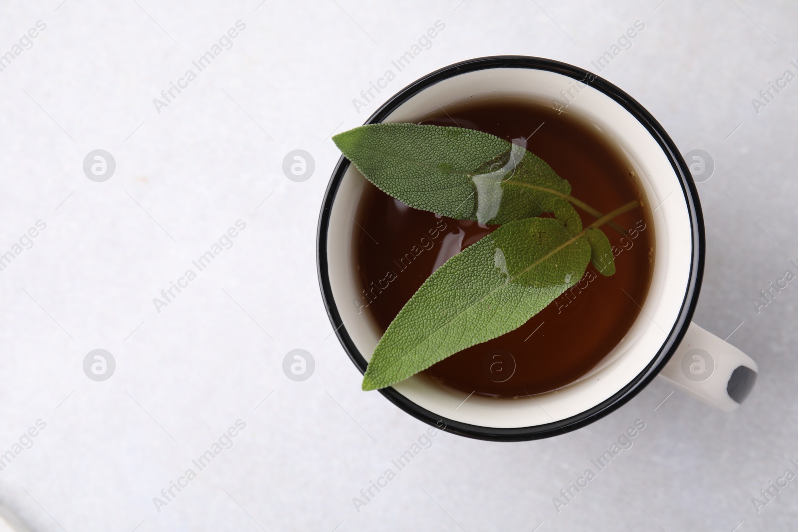 Photo of Aromatic herbal tea with sage in mug on light table, top view. Space for text