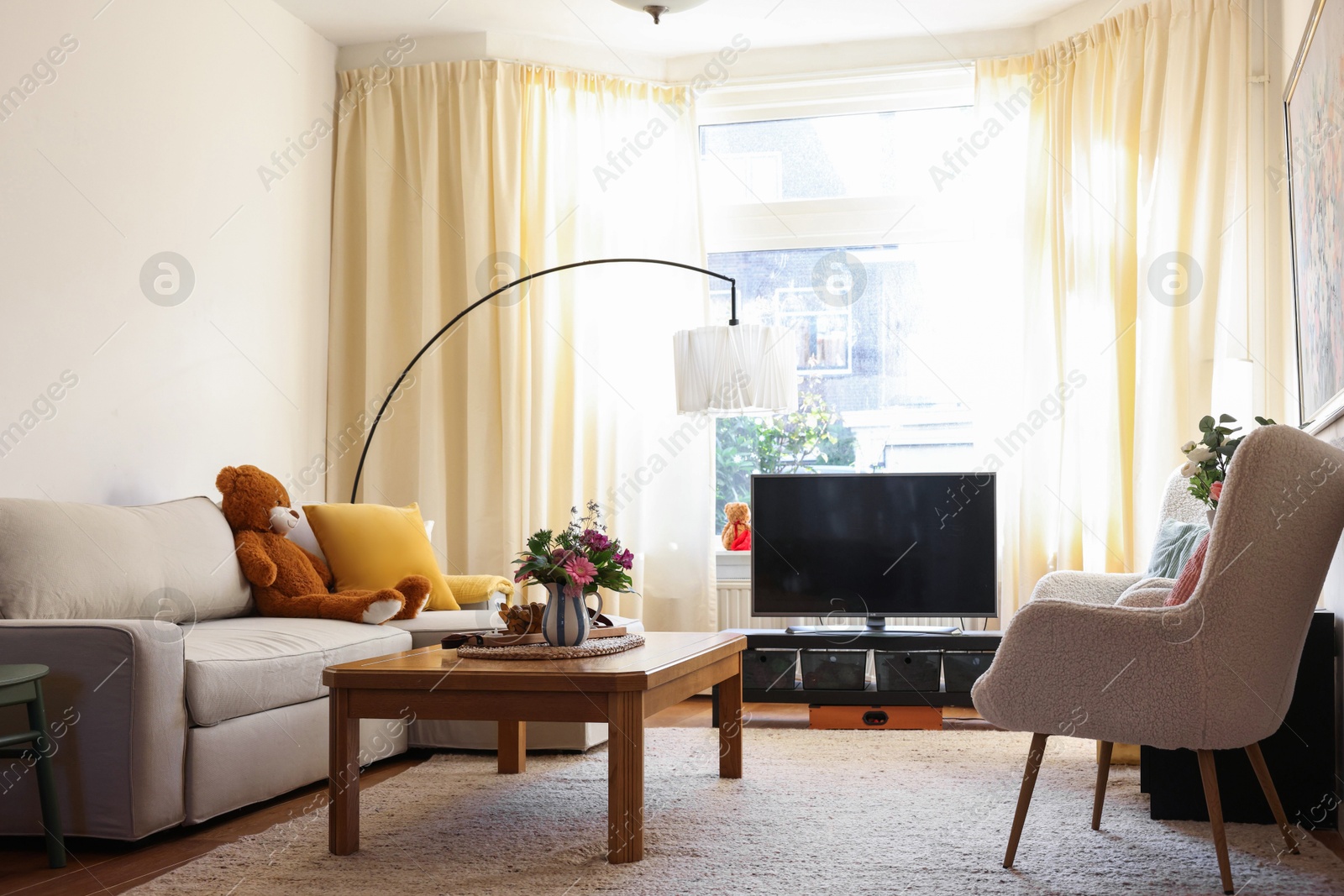 Photo of Cozy living room with modern furniture, TV set and bouquets of flowers. Interior design