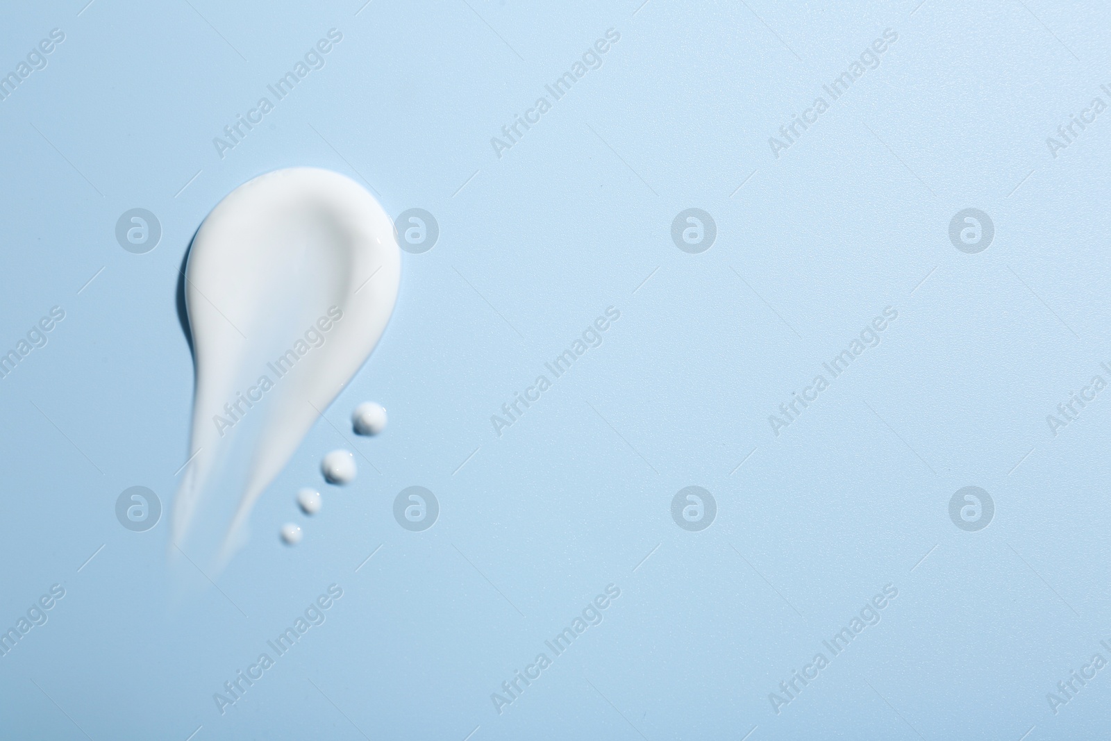 Photo of Sample of face cream on light blue background, top view. Space for text