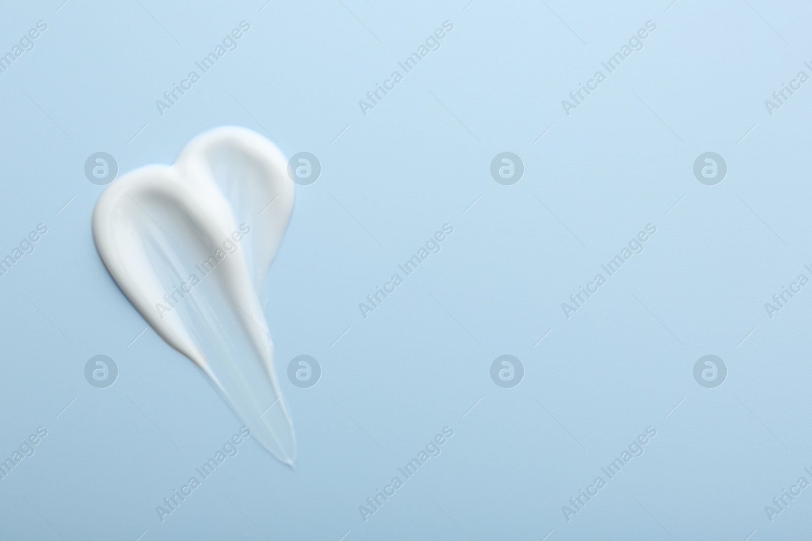 Photo of Sample of face cream on light blue background, top view. Space for text