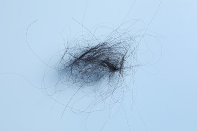 Photo of Pile of lost hair on light blue background