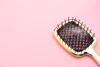 Photo of Brush with lost hair on pink background, space for text