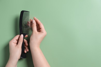 Photo of Woman taking her lost hair from comb on green background, top view. Space for text