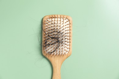 Photo of Wooden brush with lost hair on green background, top view