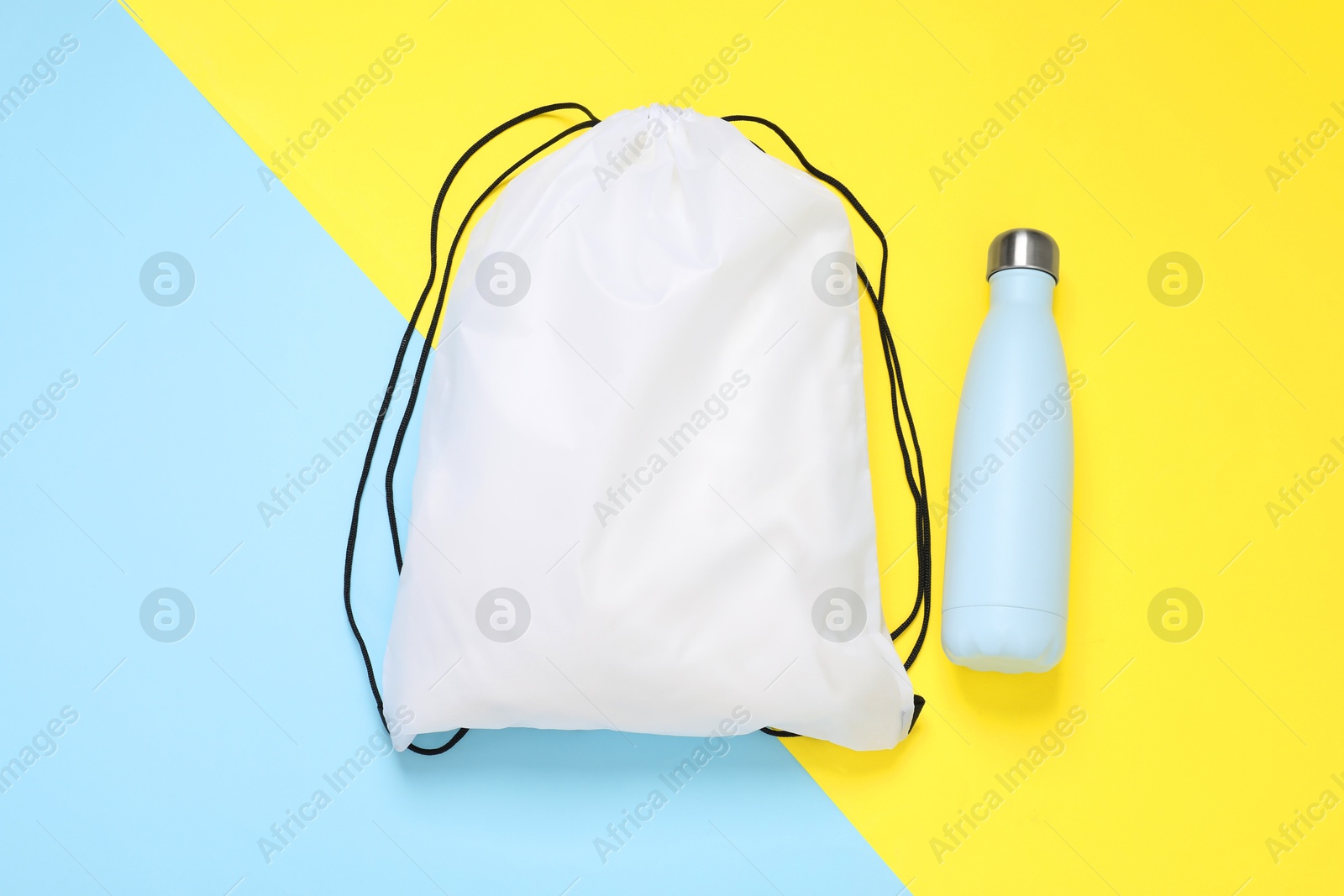 Photo of White drawstring bag and thermo bottle on color background, flat lay