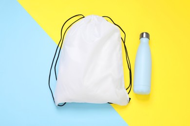 White drawstring bag and thermo bottle on color background, flat lay