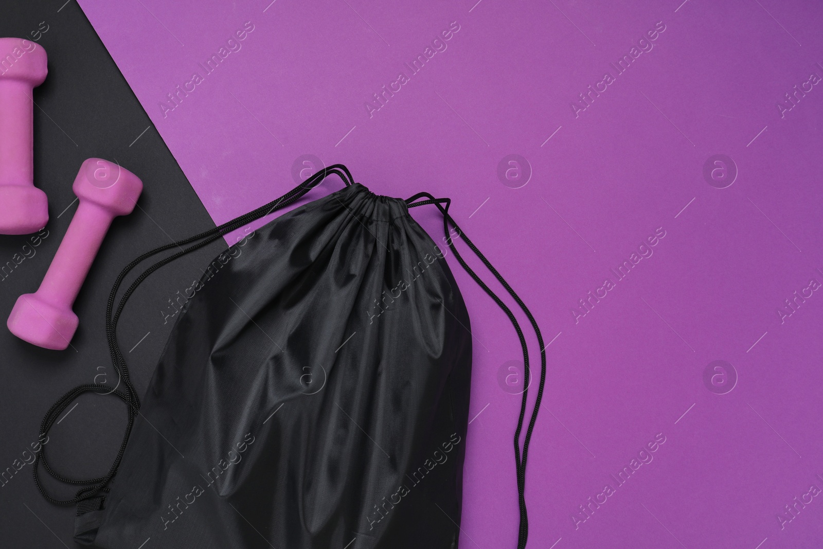 Photo of Black drawstring bag and dumbbells on color background, flat lay. Space for text