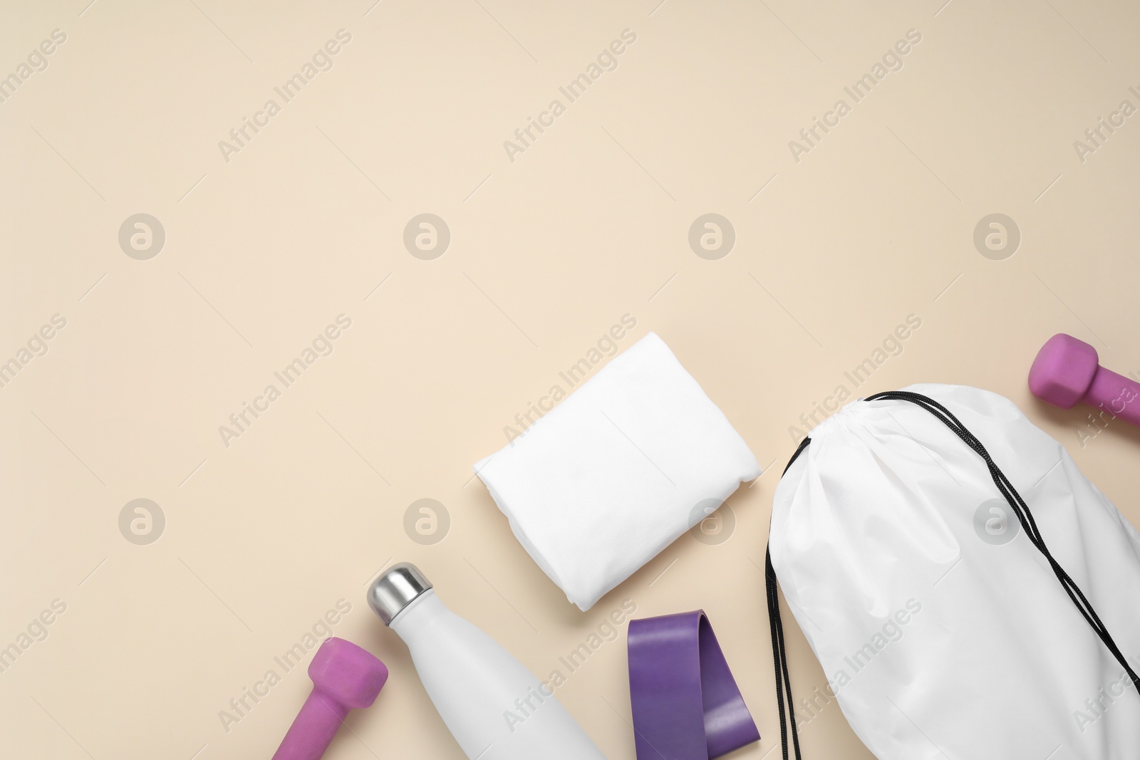 Photo of White drawstring bag and sports equipment on beige background, flat lay. Space for text