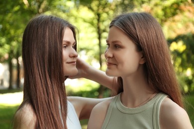 Photo of Portrait of two beautiful twin sisters in park, closeup