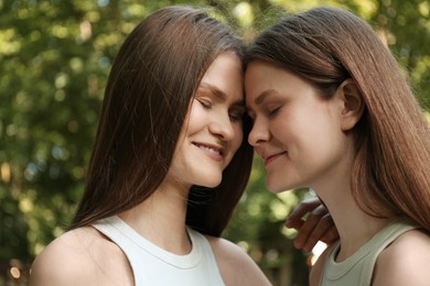 Photo of Portrait of two beautiful twin sisters in park, closeup