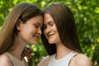 Portrait of two beautiful twin sisters in park, closeup