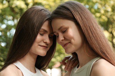 Portrait of two beautiful twin sisters in park, closeup