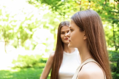 Photo of Two beautiful twin sisters in park, selective focus. Space for text