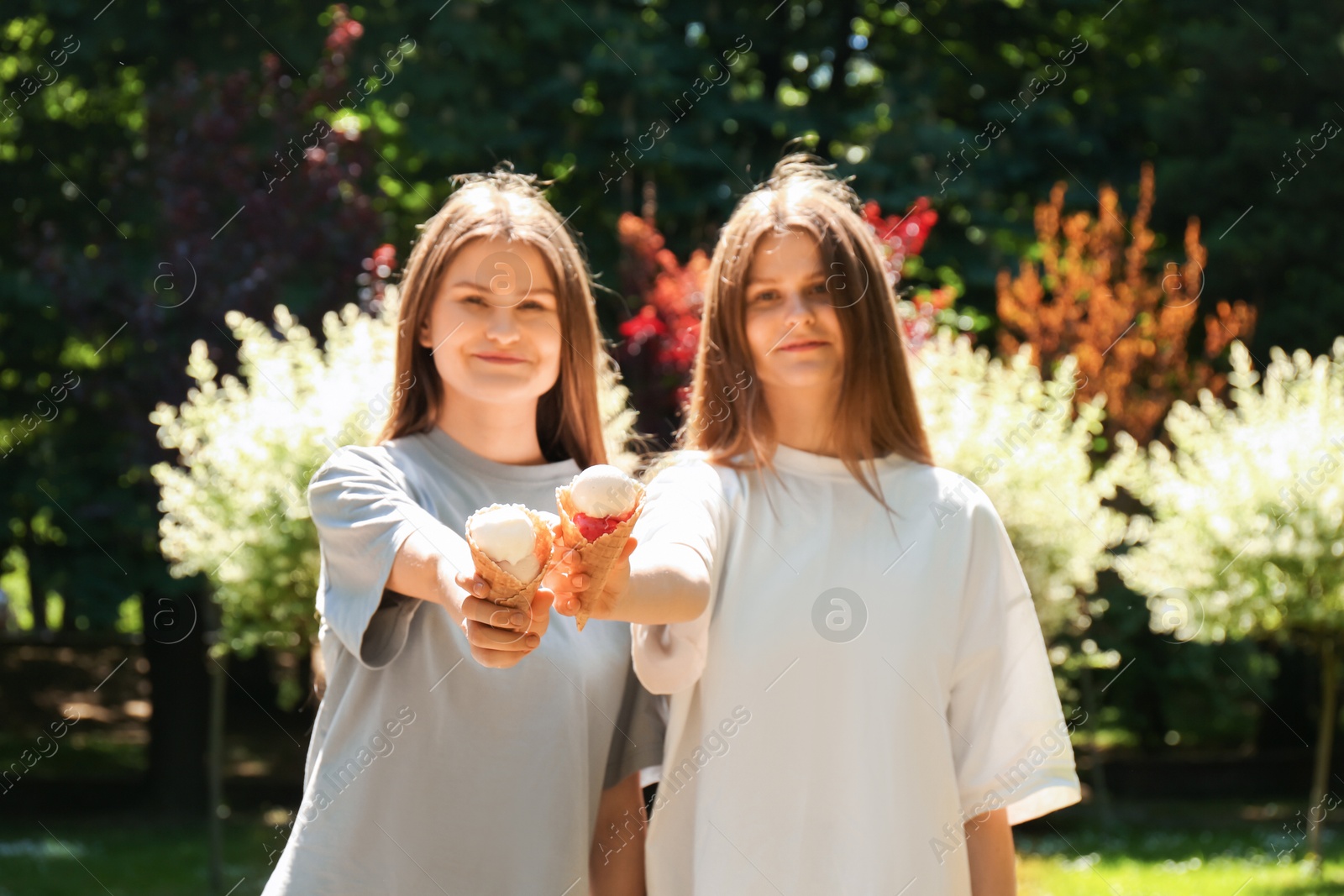 Photo of Two beautiful twin sisters with ice cream in park, selective focus