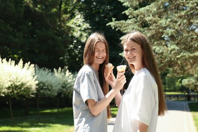 Photo of Two beautiful twin sisters with ice cream in park. Space for text