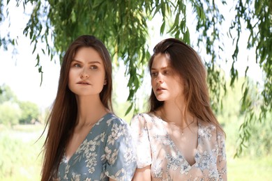 Portrait of two beautiful twin sisters in park