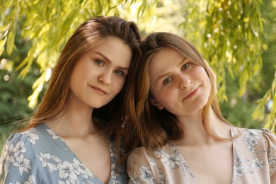 Portrait of two beautiful twin sisters in park