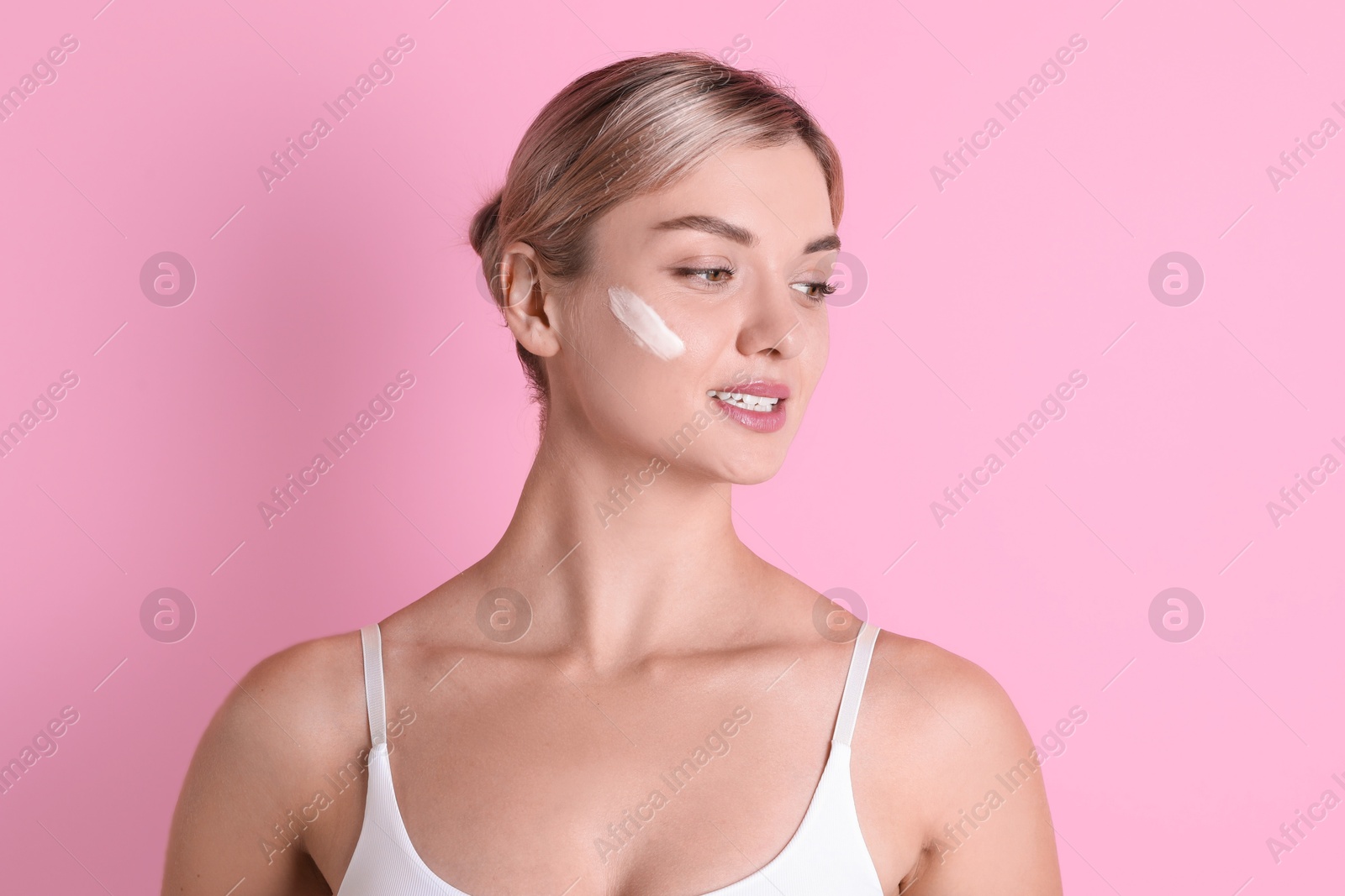 Photo of Beautiful woman with cream on her face against pink background