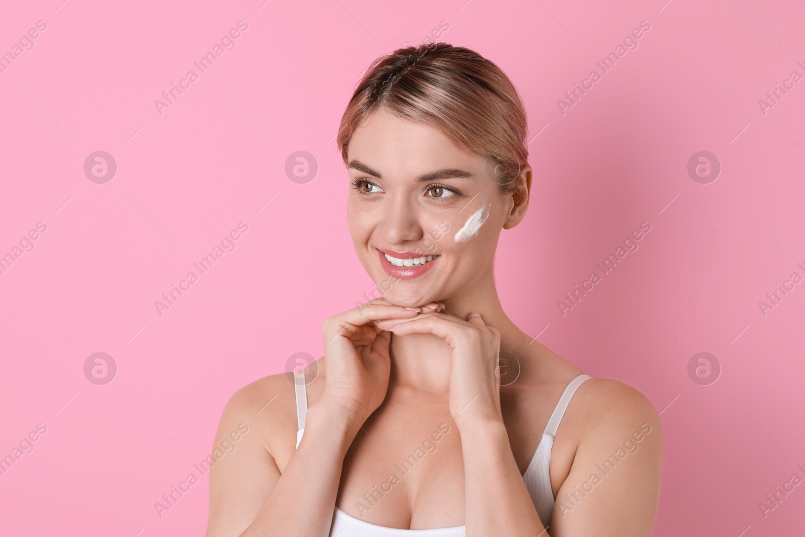 Photo of Beautiful woman with cream on her face against pink background