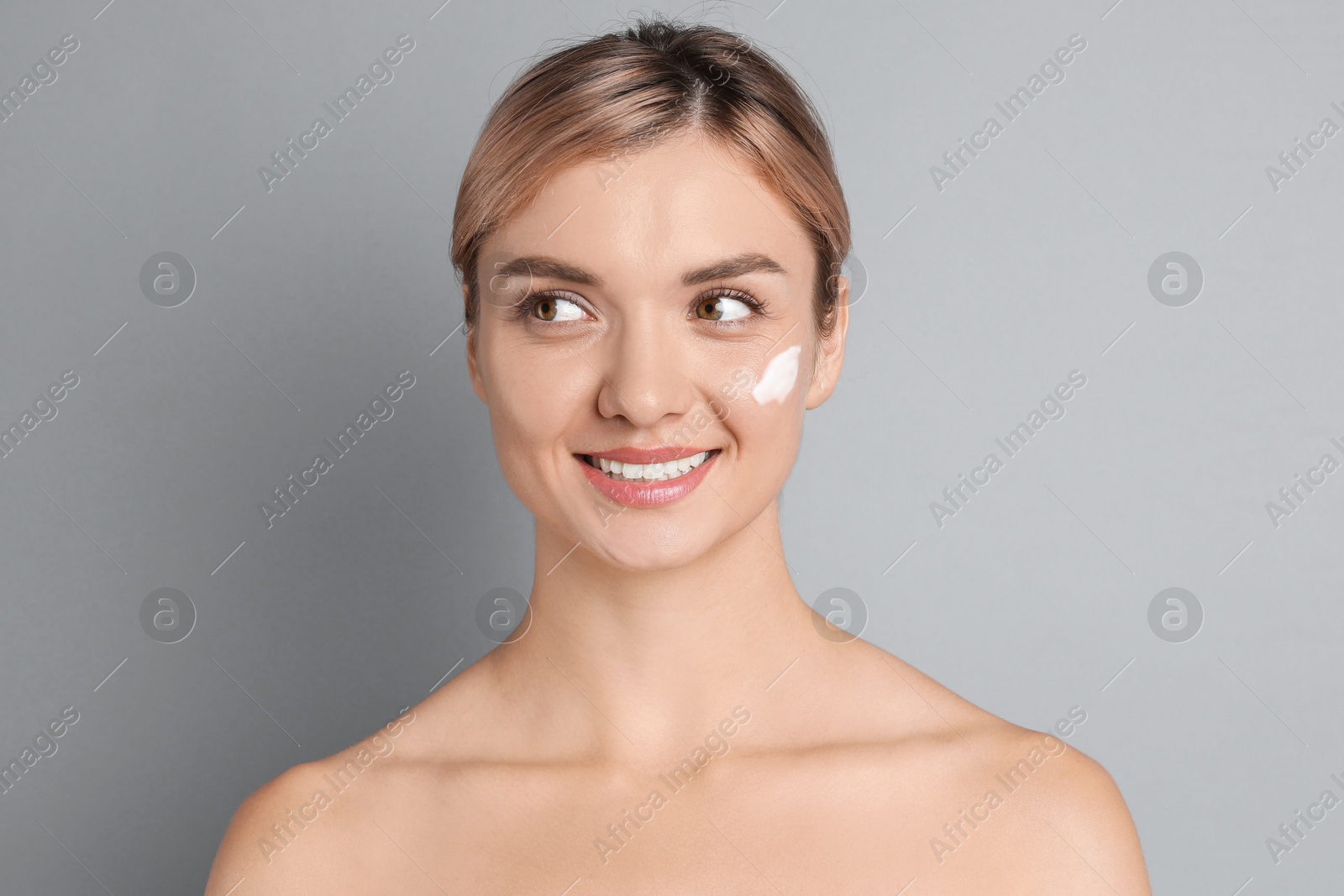 Photo of Beautiful woman with cream on her face against gray background