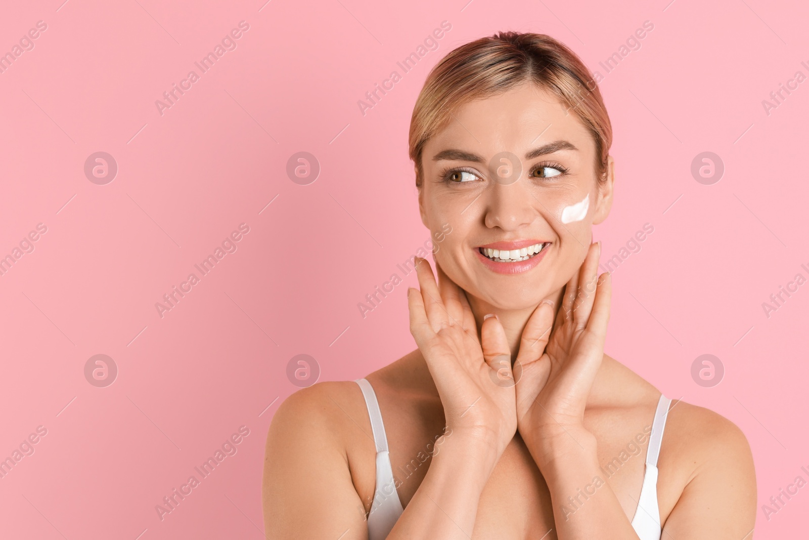 Photo of Beautiful woman with cream on her face against pink background. Space for text