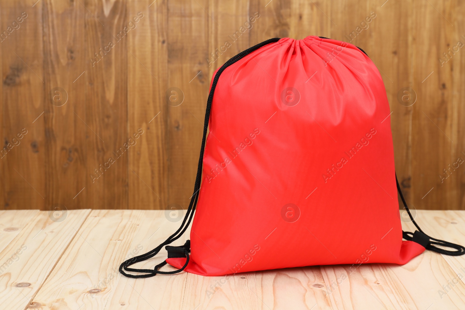 Photo of Red drawstring bag on light wooden table. Space for text