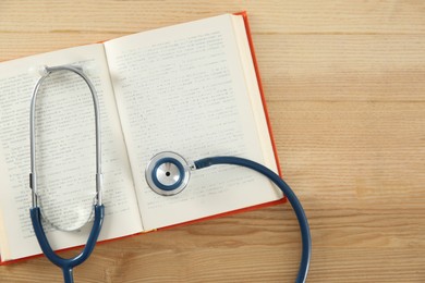 Photo of One new medical stethoscope on wooden table, top view. Space for text