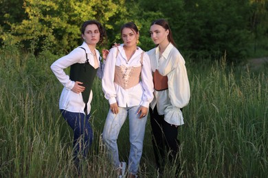 Beautiful women in stylish corsets posing outdoors