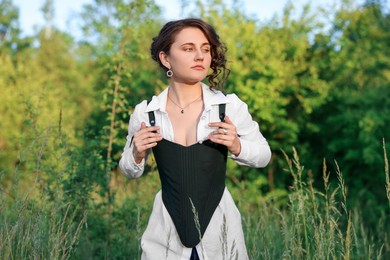 Beautiful woman in black corset posing outdoors