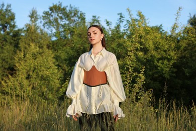 Photo of Beautiful woman in stylish corset posing outdoors