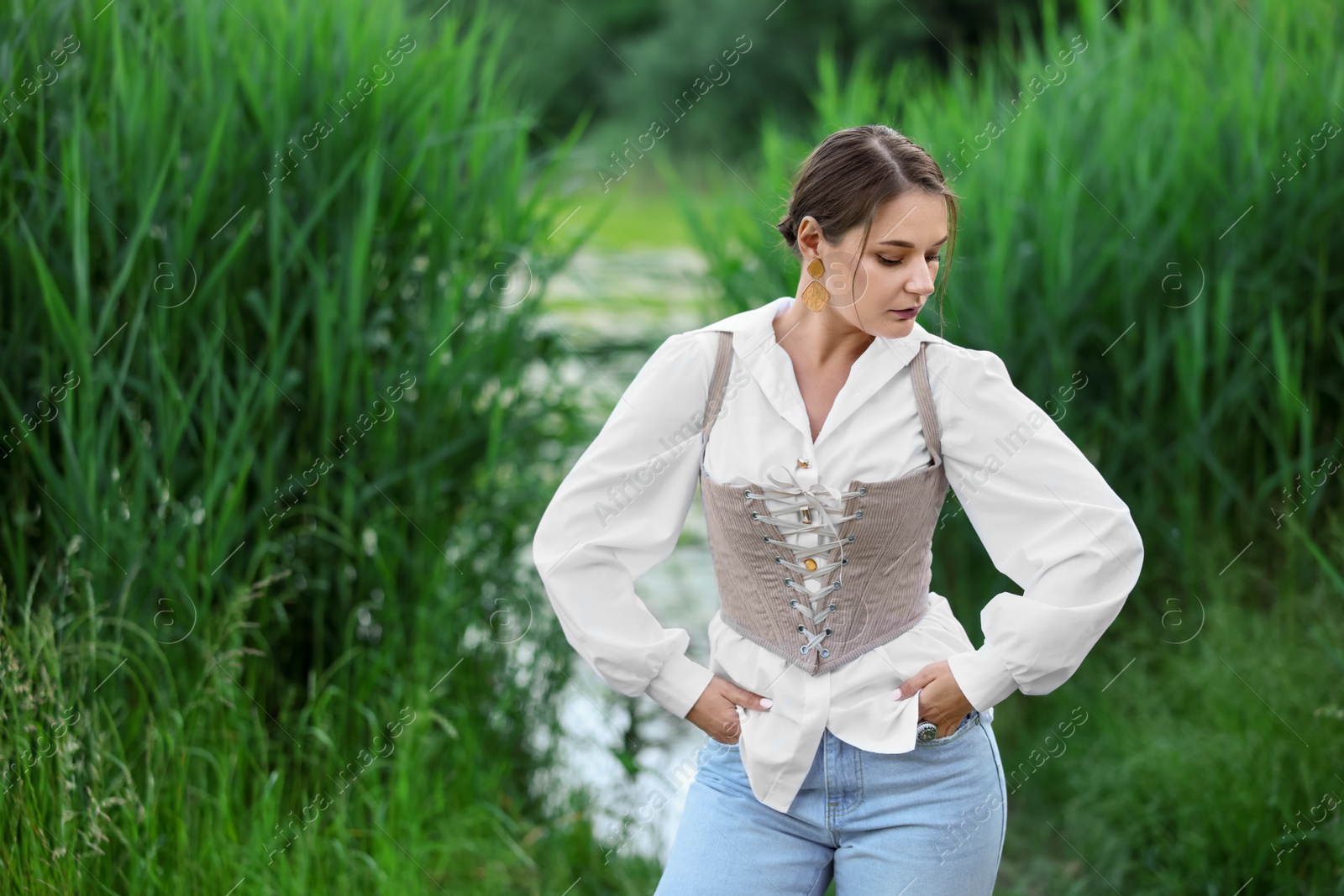 Photo of Beautiful woman in stylish corset posing outdoors. Space for text