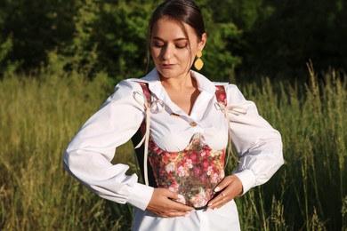 Beautiful woman in stylish corset posing outdoors