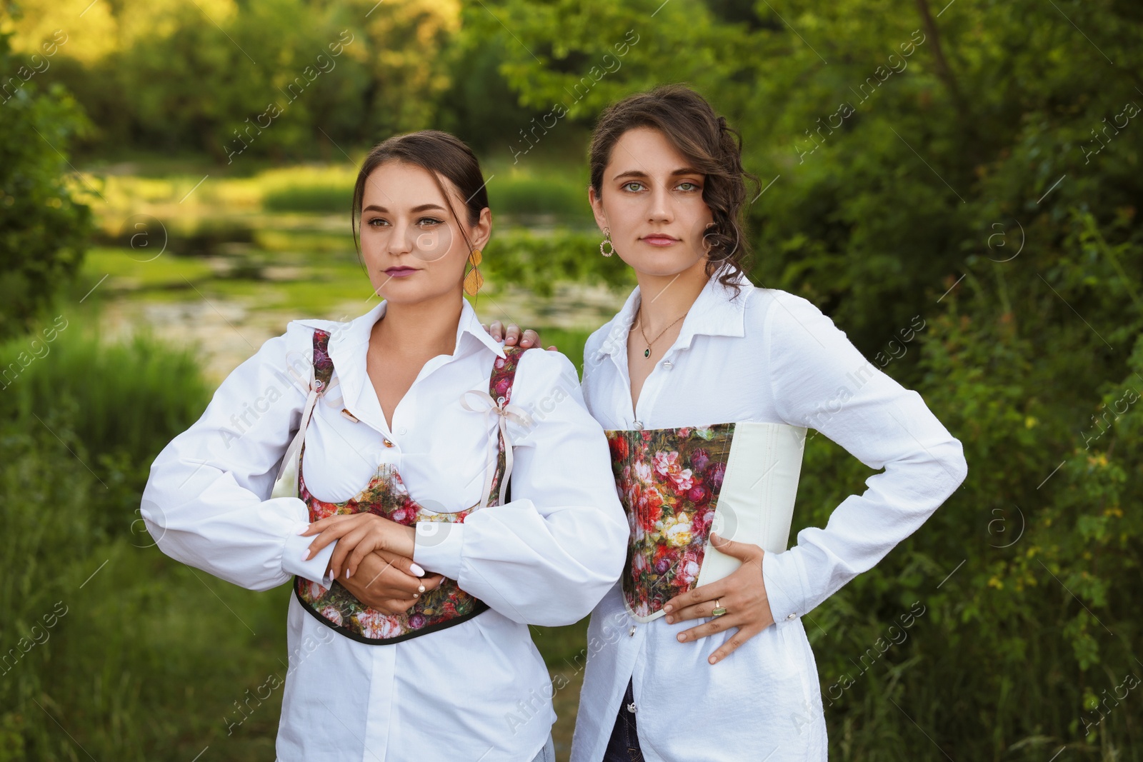 Photo of Beautiful women in stylish corsets posing outdoors