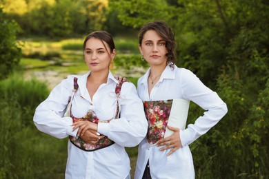 Beautiful women in stylish corsets posing outdoors