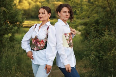 Beautiful women in stylish corsets posing outdoors