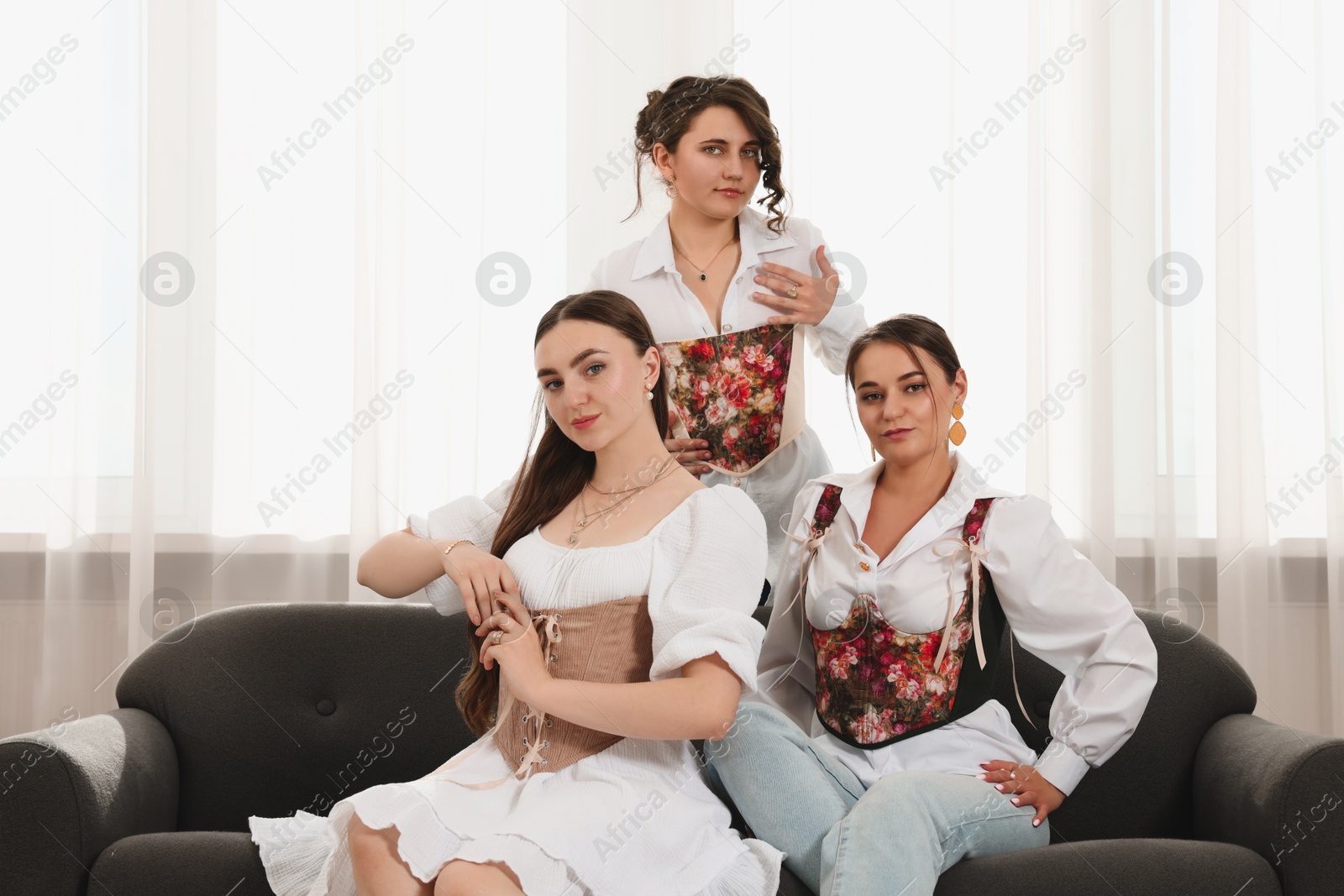 Photo of Beautiful women in stylish corsets posing indoors