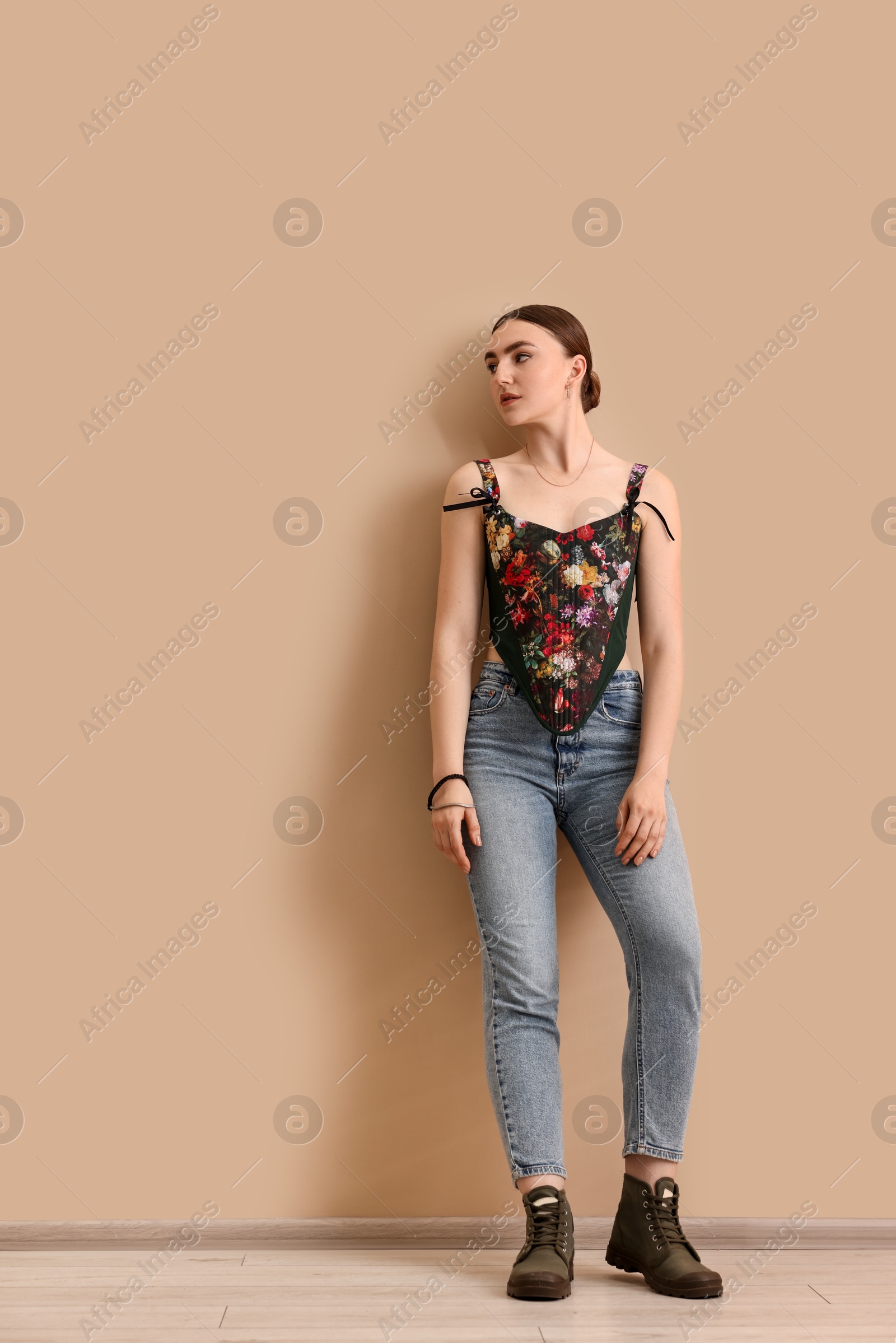 Photo of Beautiful young woman in stylish corset near beige wall