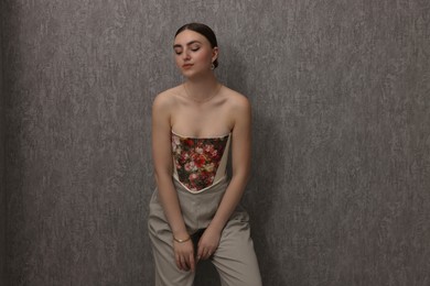 Photo of Beautiful young woman in stylish corset near grey wall