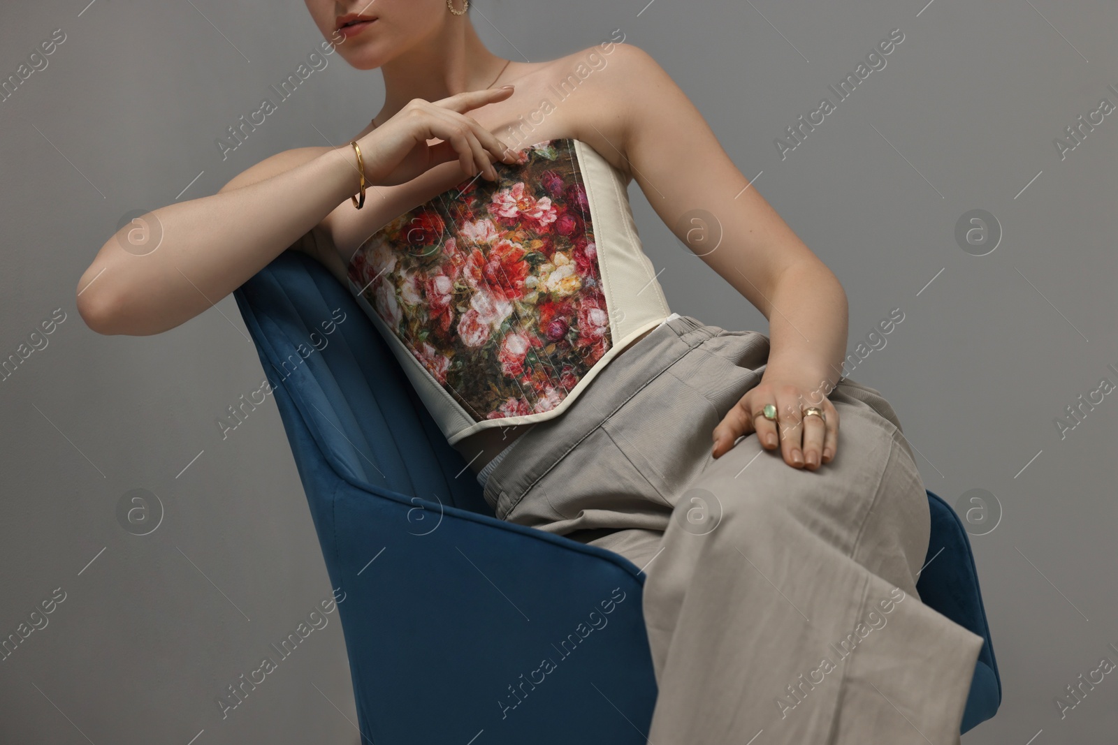 Photo of Woman in stylish corset on armchair indoors, closeup