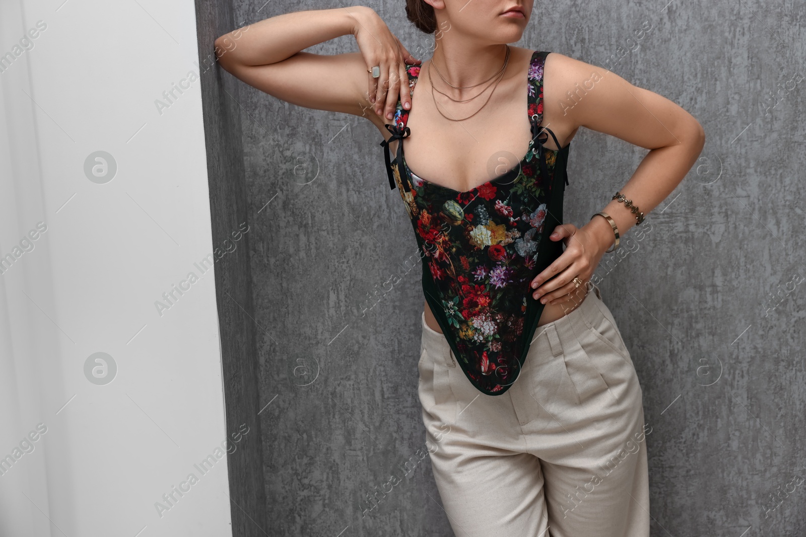Photo of Woman in stylish corset near grey wall, closeup