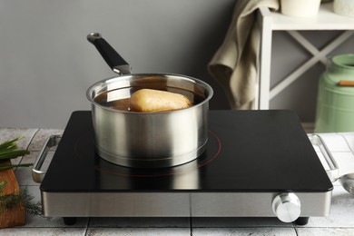 Boiling potatoes in saucepan on stove in kitchen