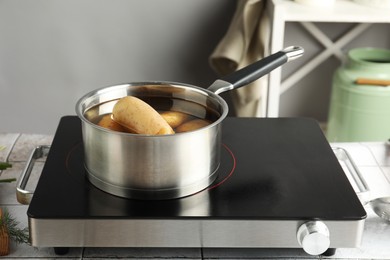 Boiling potatoes in saucepan on stove in kitchen