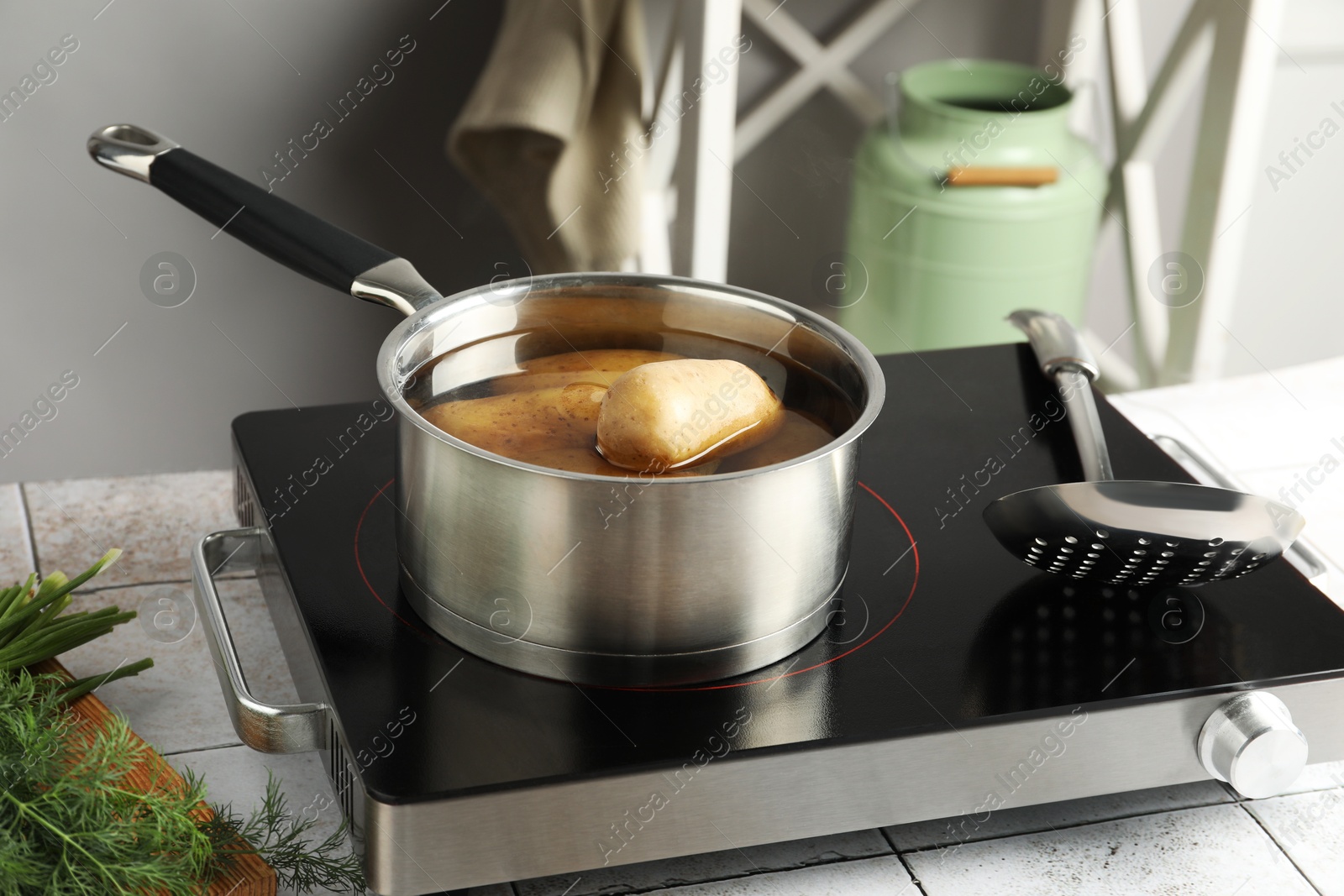 Photo of Boiling potatoes in saucepan on stove in kitchen