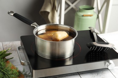 Boiling potatoes in saucepan on stove in kitchen